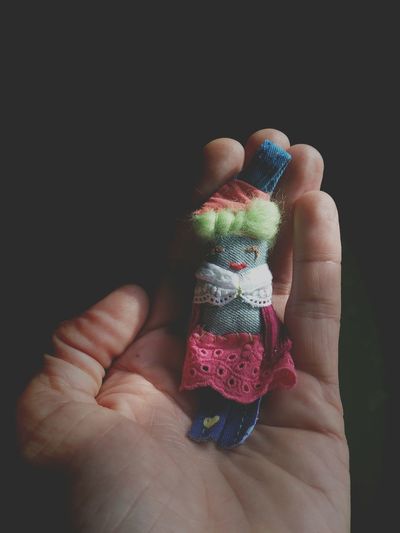 Cropped image of person holding doll against black background