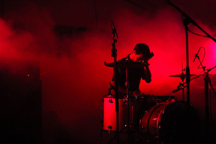Drummer sitting by drums during music concert