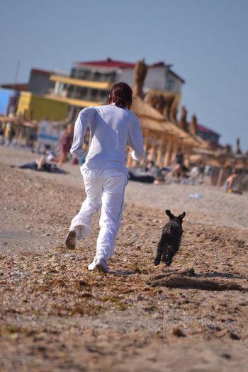 Rear view of woman with dog running at beach