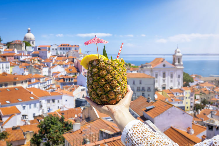 Rear view of woman holding pineapple against sky