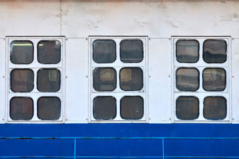Three cabin windows and portholes on outboard side of ship. close up of hull of vintage ocean liner