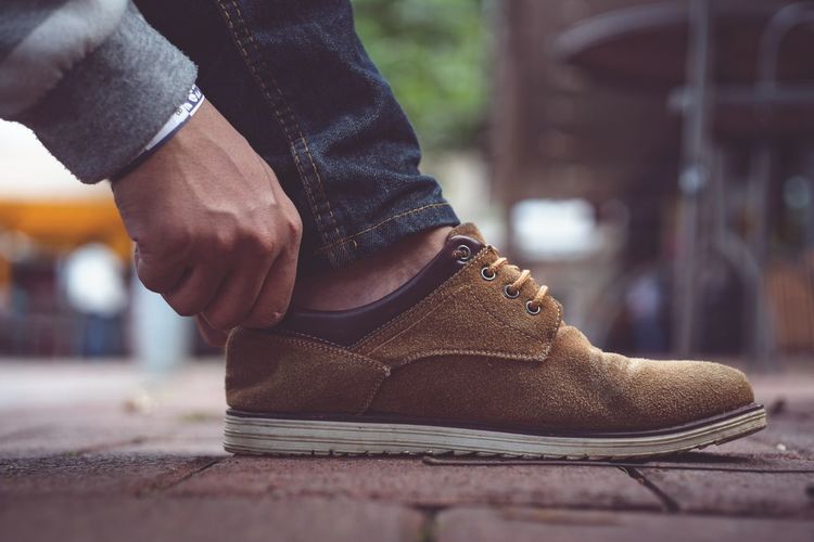 Low section of man wearing leather shoes on footpath