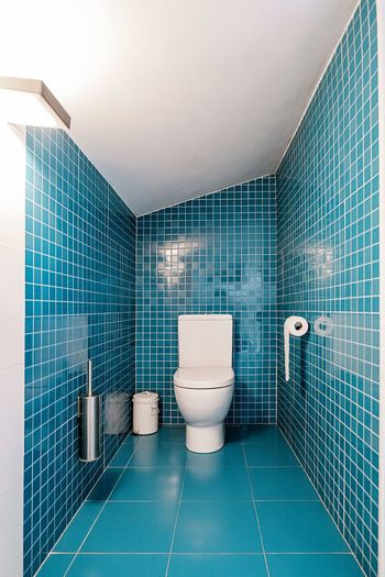 Front view of blue tiles walls in spacious modern bathroom in daylight
