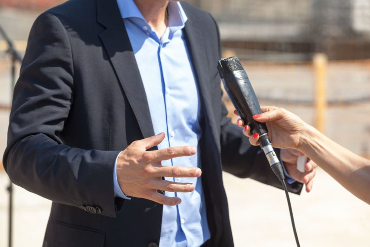 Cropped hand of female journalist interviewing businessman