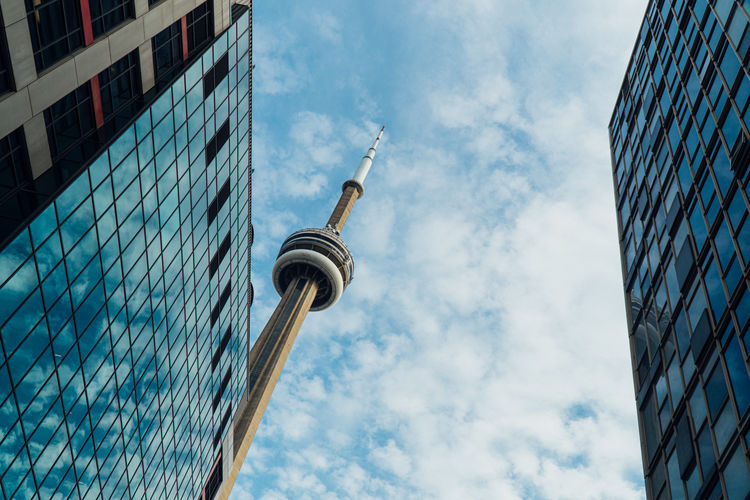 Low angle view of modern buildings against cloudy sky