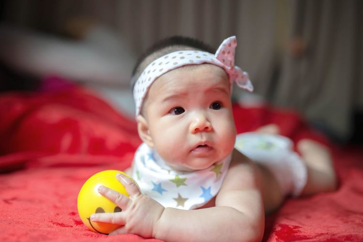 Cute baby girl with toy on bed