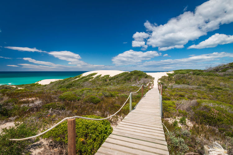 Scenic view of wooden boardwalk leading to sea at de hoop nature reserve south africa against sky
