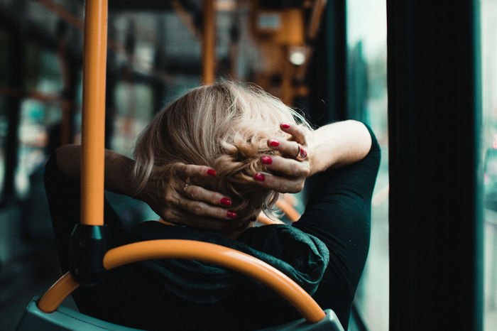 Rear view of woman adjusting hair while traveling in bus