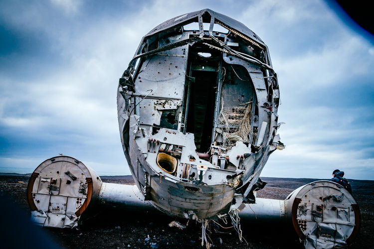 Abandoned military airplane at beach against cloudy sky during winter
