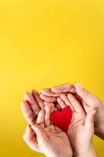 Close-up of man holding hands against yellow background