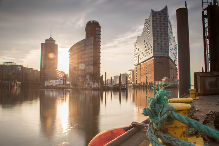 Rope tied on cleat at harbor against buildings during sunset