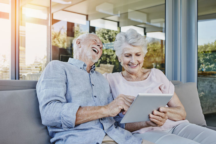Senior couple sitting on terrace using digital tablet