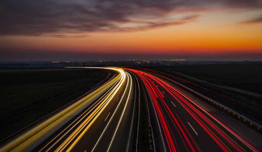 High angle view of light trails on highway at sunset