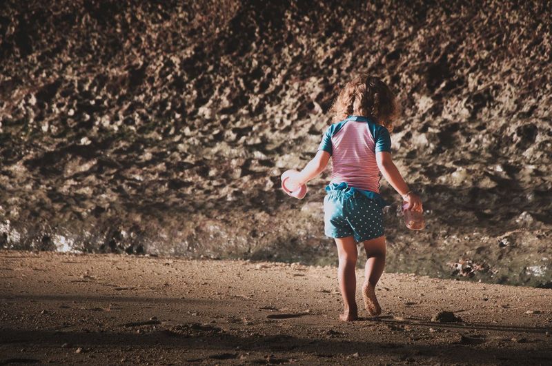 Rear view of girl walking on sand at beach