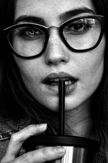 Close-up portrait of woman wearing eyeglasses while having drink