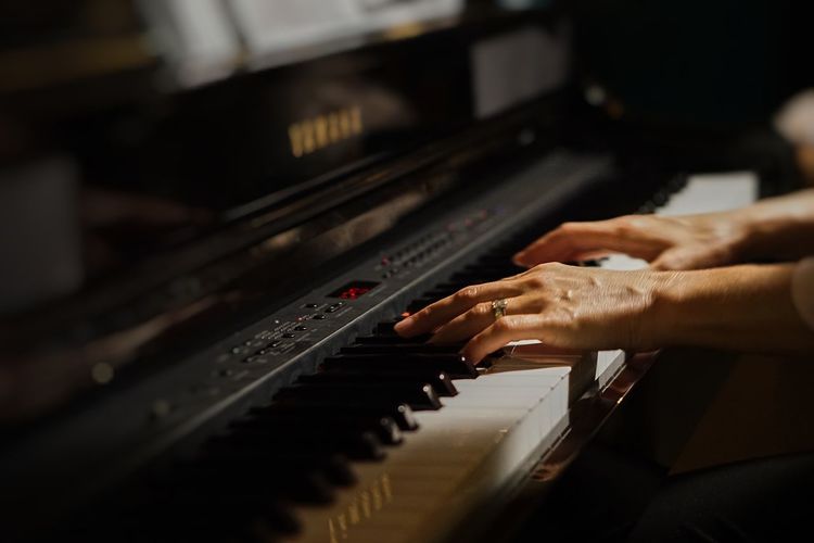 Cropped hands of woman playing grand piano