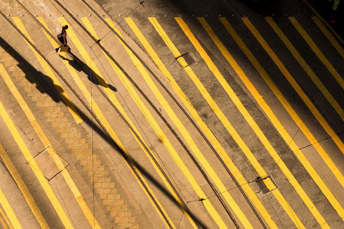 High angle view of woman walking on yellow striped street