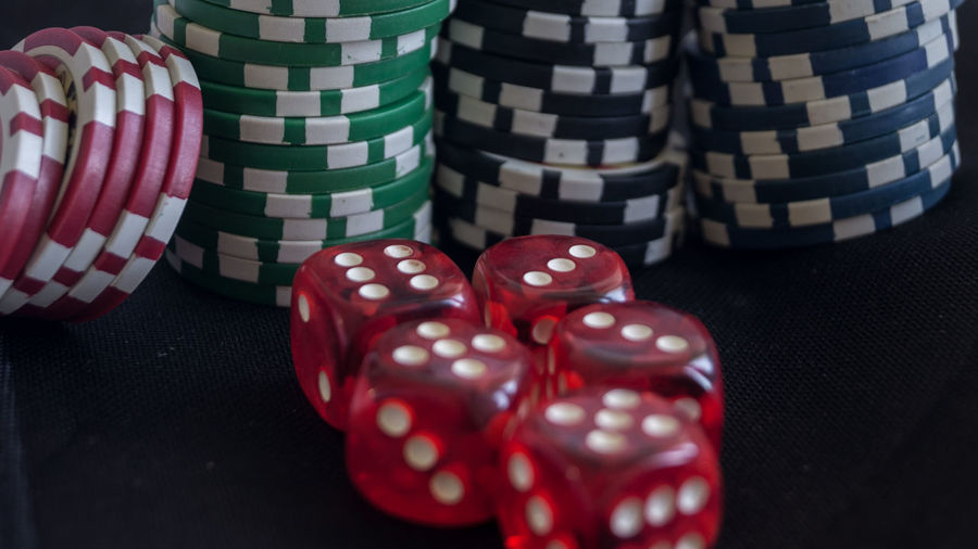 Close-up of red dice and gambling chips on black table