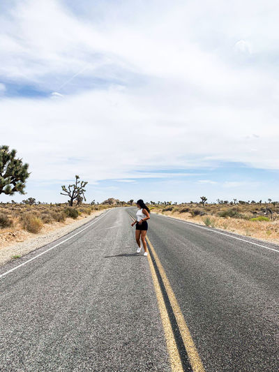 Full length of woman running on road against sky