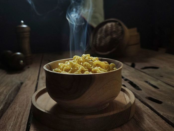 A bowl of hot boiled noodles is ready to eat in a wooden table. dark mood photography concept