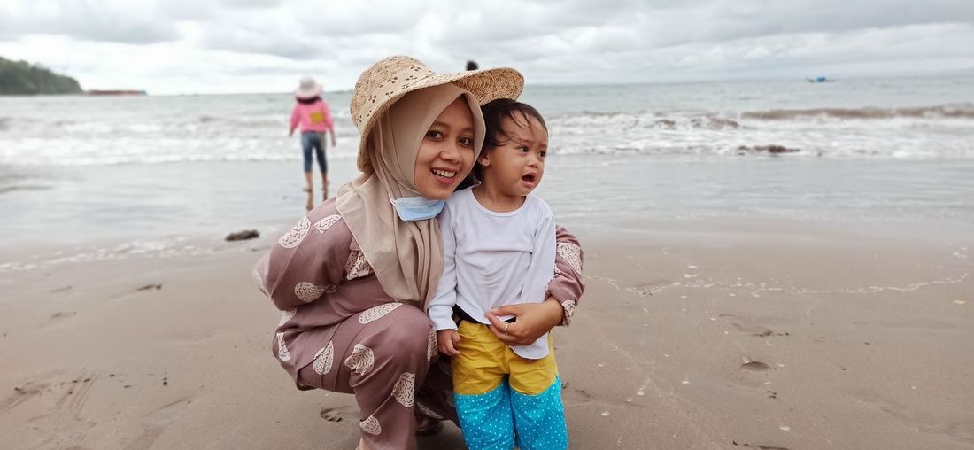 Portrait of smiling mother with crying daughter at beach